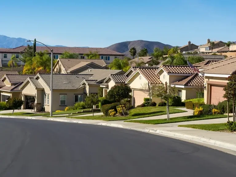 Suburban neighborhood with stucco houses and mountain backdrop.