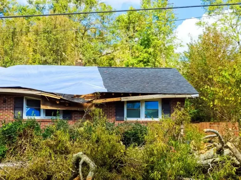 Damaged house roof covered with a tarp after storm damage.