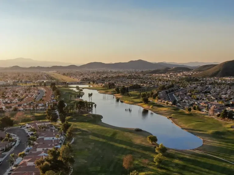 Aerial view of a suburban golf course with a lake at sunset.